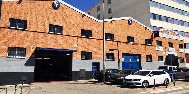 Fachada de ladrillo de Carrocerías Leal con sus portones azules